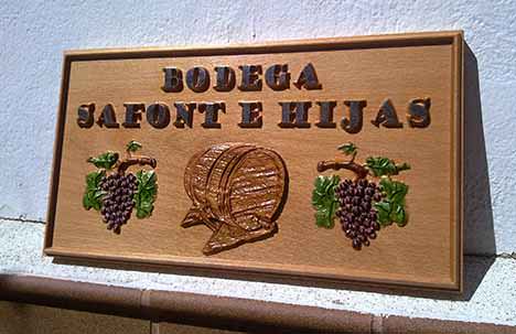 cartel de madera para bodega con racinos de uvas y un tonel de vino. Además tiene el nombre de la Bodega Safont e Hijas. 