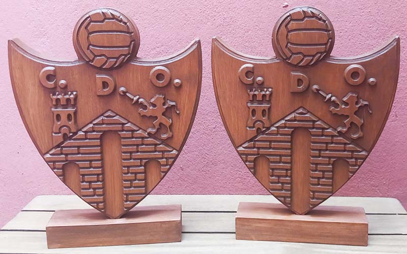 Trofeos de madera con forma de escudo sobre bases de madera